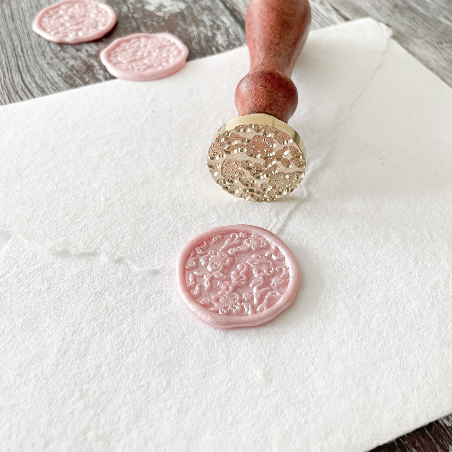 Pink envelope seal made with a floral wax stamp and eco friendly sealing wax.  Using the summer Garden wax seal stamp from By The Natural Paper Company
