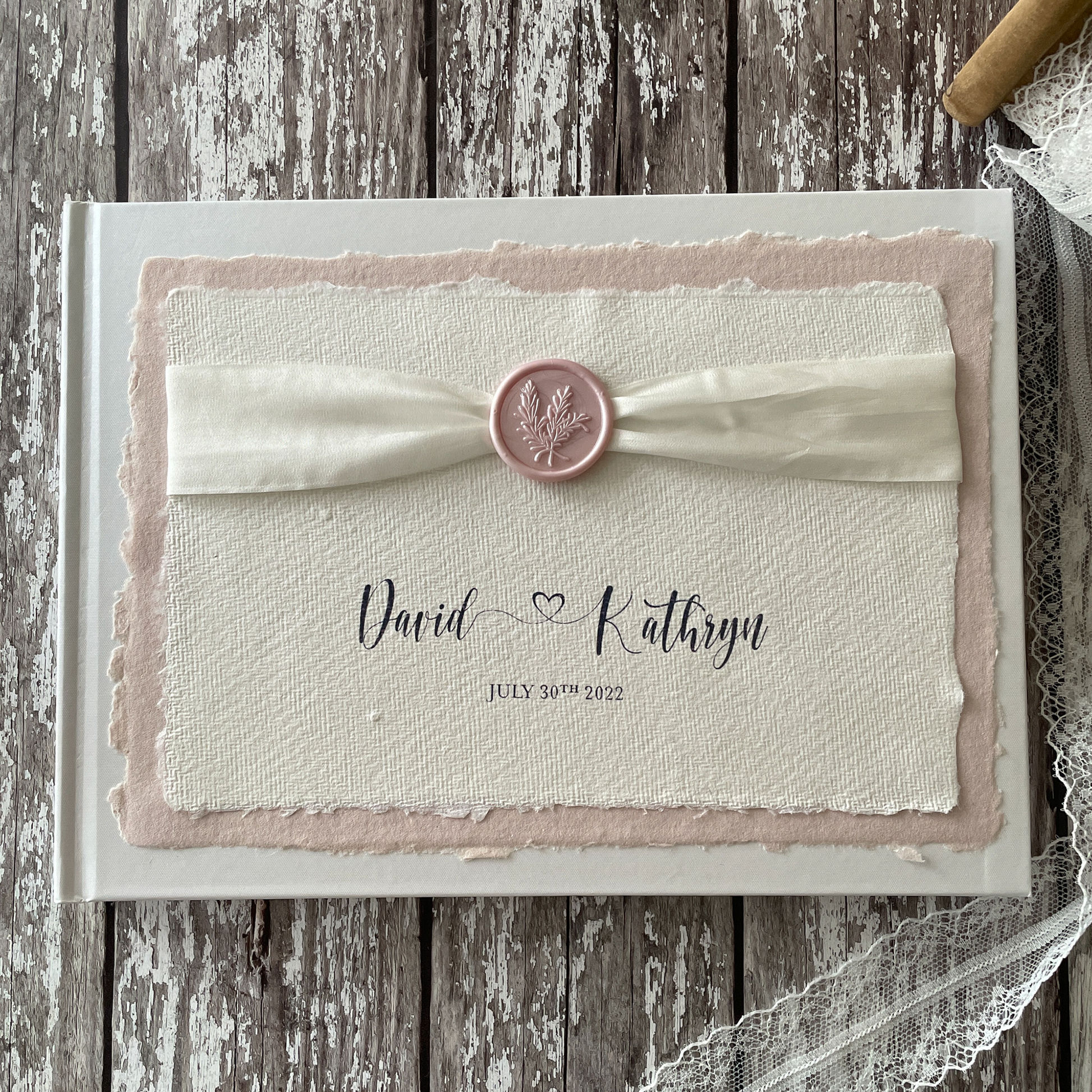 Personalised wedding guest book made from eco friendly materials By The Natural Paper Company.  Handmade paper guest book, recycled cotton rag paper and card; Silk Ribbon and a Wax seal in ivory and blush pink.  