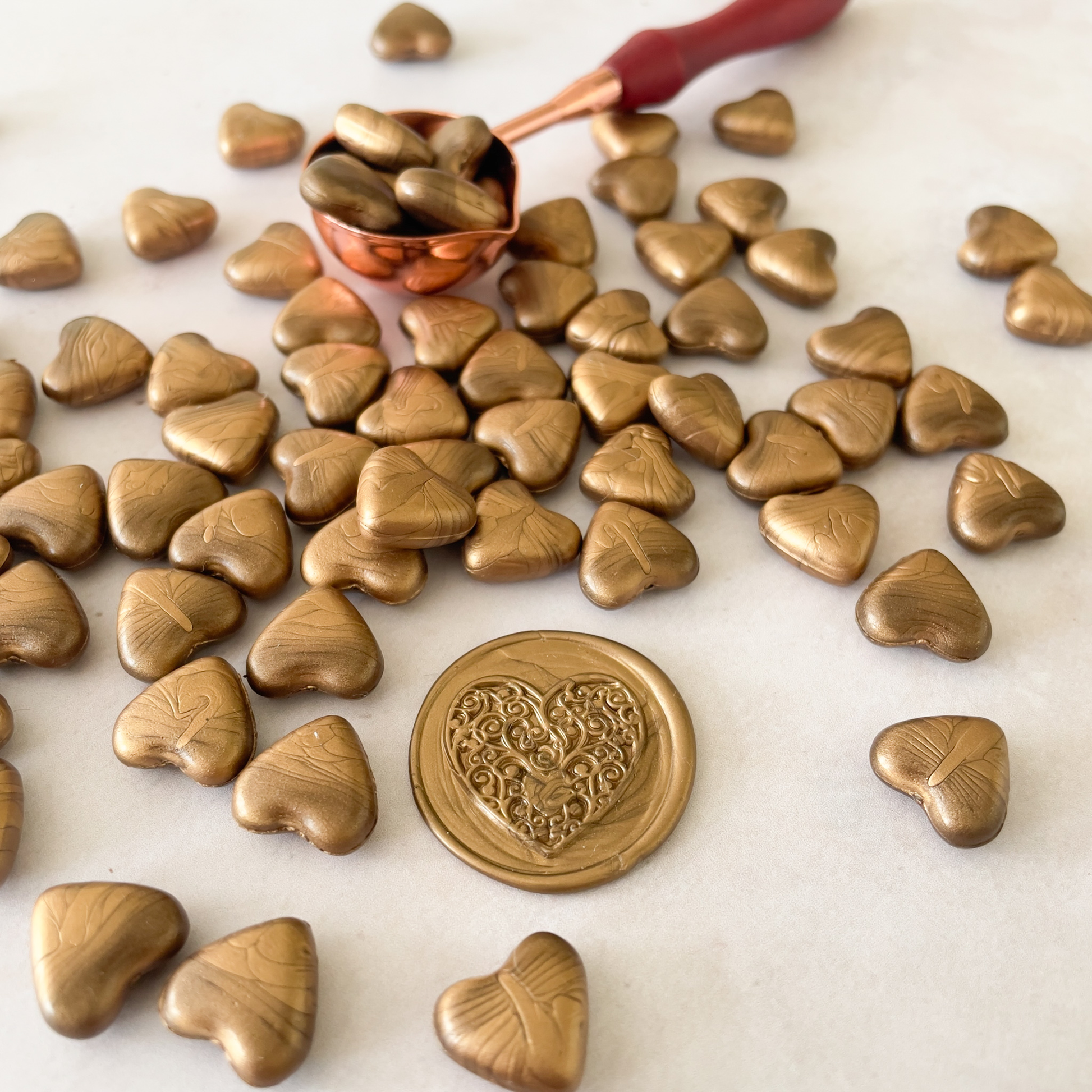 gold sealing wax beads in the shape od a heart.  Small beads of wax to make wax seals and stamps