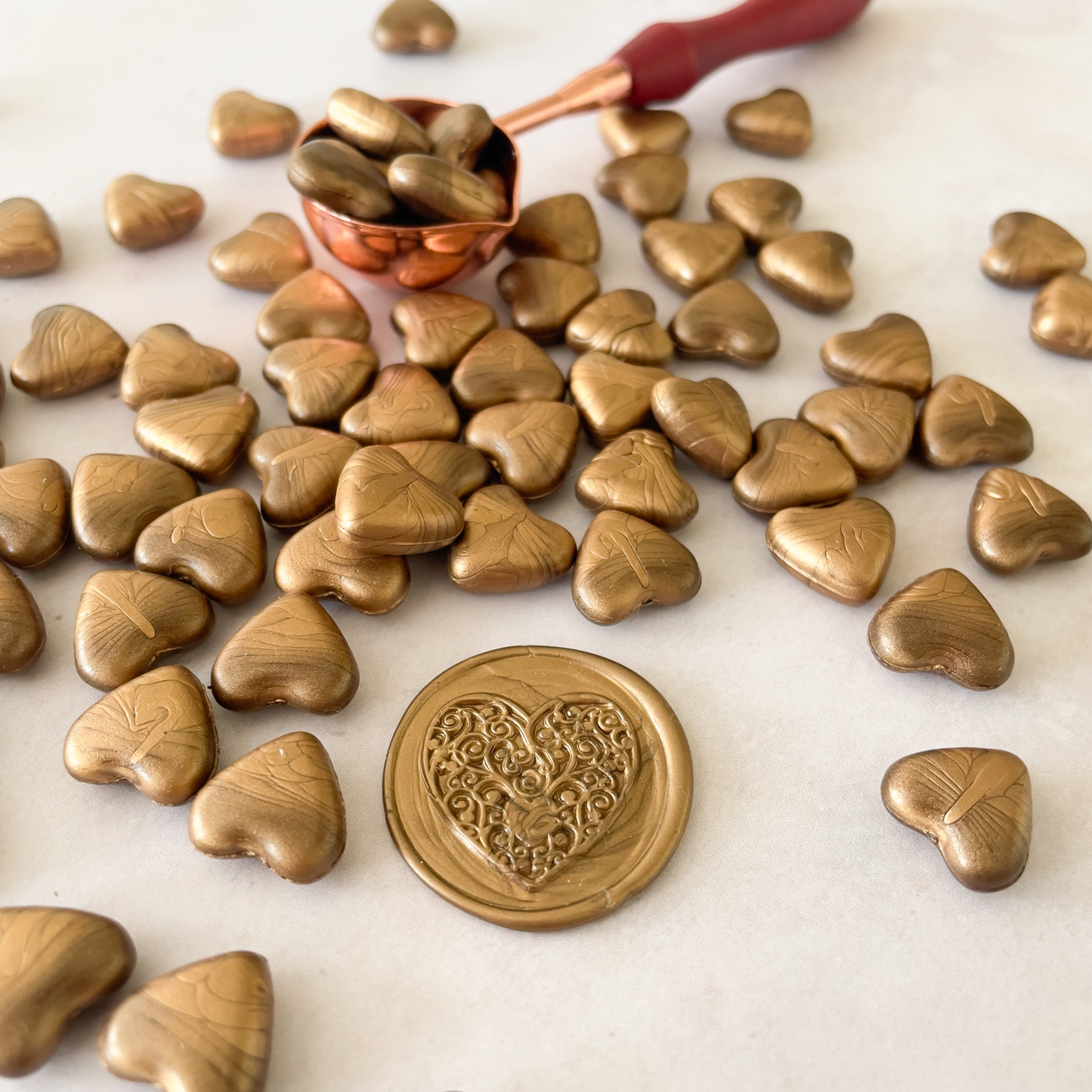 warm gold sealing wax beads in the shape of a heart.  Wax beads to make stamps and seals.