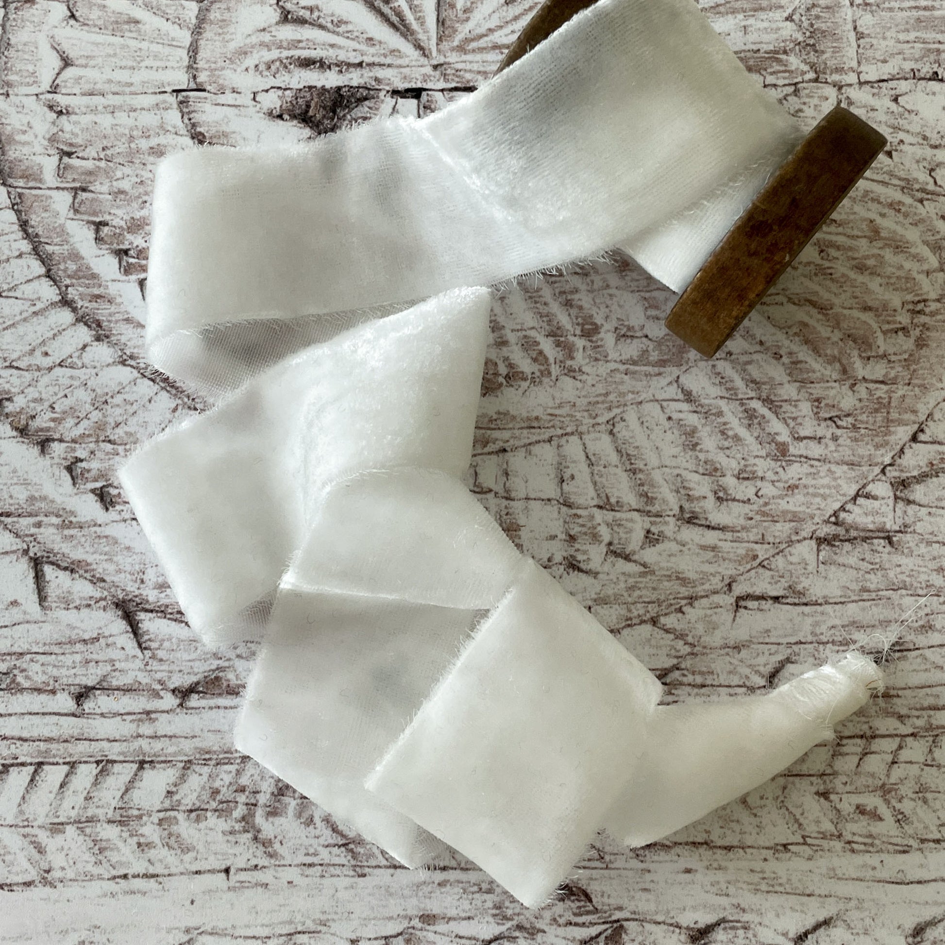 white silk velvet ribbon.  Luxury velvet ribbon made from silk.  Velvet ribbon with frayed edge in white.  Roll of lightweight velvet ribbon